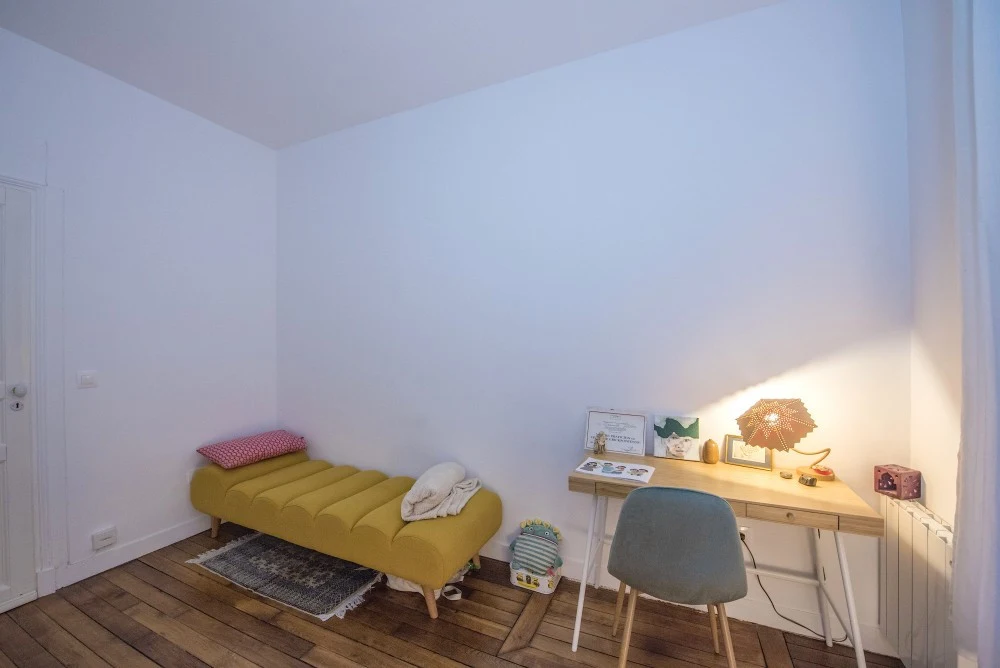 Espace de travail du cabinet : bureau en bois éclairé par une lampe et banquette jaune